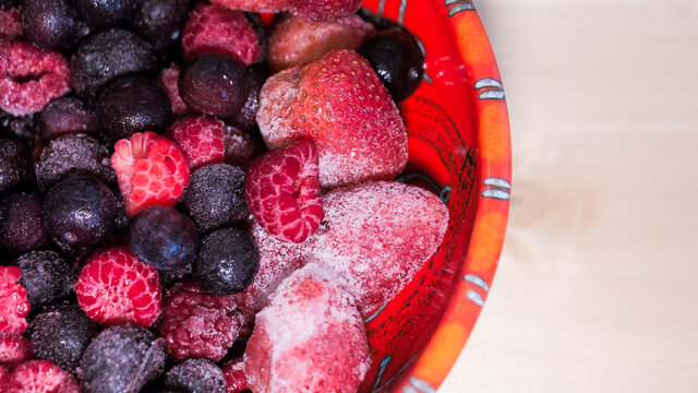 Vista cenital de deliciosos y frescos frutos rojos congelados como frutillas ar&aacute;ndanos y frambuesas ideales para prepara un pastel dulce y sabroso. 