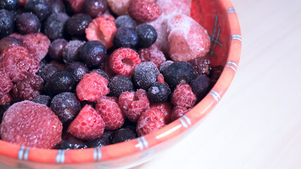 Vista cenital de deliciosos y frescos frutos rojos congelados como frutillas arándanos y frambuesas ideales para prepara un pastel dulce y sabroso. 