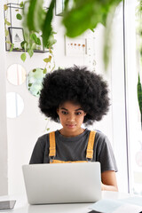Happy stylish hipster African American female hipster student with Afro hair using laptop computer...