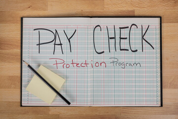 Paycheck protection program on a business ledger with pencil and posted note 