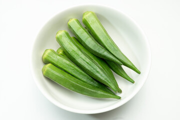 Okra in a white ceramic bowl. (White background.)