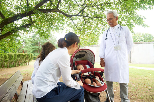 かかりつけのお医者さんとおばあちゃんと娘と生まれて3か月の女の子の赤ちゃん 患者 グリーンバック