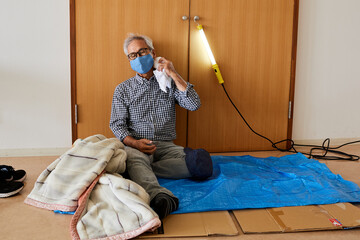 避難所イメージ　災害にあって避難所の体育館に避難してきたシニア男性