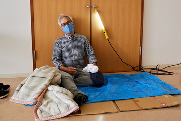 避難所イメージ　災害にあって避難所の体育館に避難してきたシニア男性