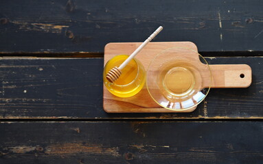 The idea of natural products. On a dark wooden background on a kitchen board there is honey and a spoon with honey.