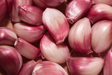 close-up of a set of loose purple garlic cloves on a wooden background.