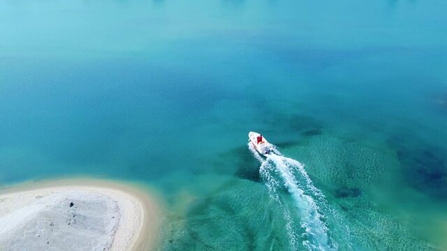 Motorboat passing between to sand beaches on blue clear sea. Aerial view 