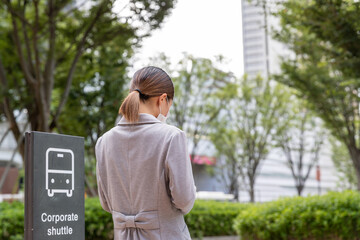 バス停でスーツケースを持ってバスを待つ女性