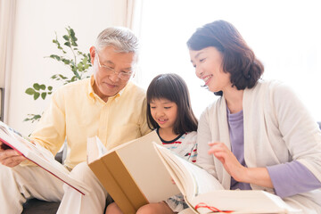 本を読む祖父母と孫