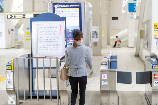 マスク姿で改札を通る働く女性