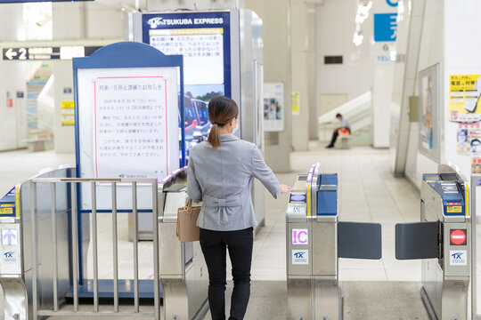 マスク姿で改札を通る働く女性