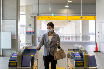 マスク姿でエスカレーターに通勤で乗る女性