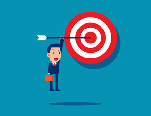 A businessman hanging on an arrow that sticks out of the target