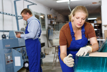 Fototapeta na wymiar Portrait of qualified female glazier during daily work in glass factory..