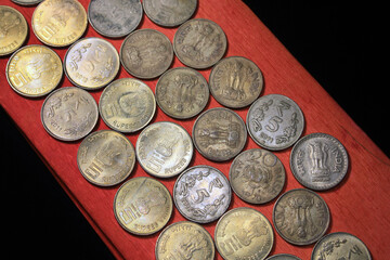 Stock pile of 1, 2, 5, 10 Indian rupee metal coin currency isolated on sack background. Financial, economy, Banking and exchange investment concept. 5 rupee coin highlighted.