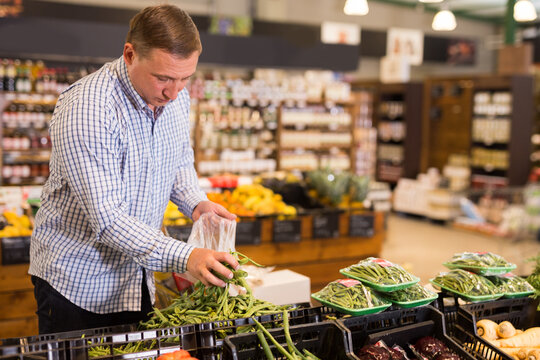 Man choosing green beans at grocery store. High quality photo
