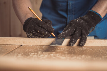 CLose up of the carpenter with a pencil and tape measure mark on wooden board on table....