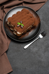 Classic tiramisu dessert on ceramic plate on concrete background