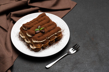 Classic tiramisu dessert on ceramic plate on concrete background