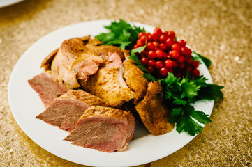 Chicken baked meat with herbs. Chicken breast slices on white plate, isolated on table.