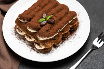 Classic tiramisu dessert on ceramic plate on concrete background