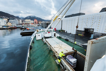 Fototapeta na wymiar Unloading cargo with a crane on the mailboat MS Lofoten of norwegian coastal line Hurtigruten lying in port in Bergen