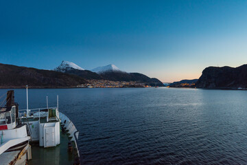 Arriving in Maloy, Norway with cruise ship in early morning with snow capped mountains on clear winter day