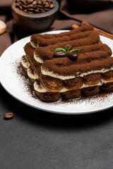 Classic tiramisu dessert on ceramic plate and savoiardi cookies on concrete background
