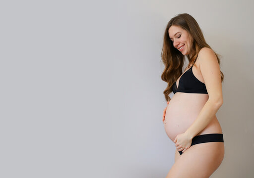 Pregnant woman wearing support underwear and holding belly - Stock Image -  C054/1961 - Science Photo Library