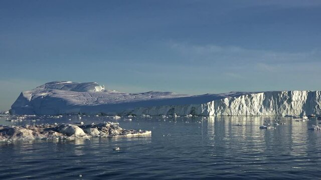 Antarctica. Beautiful blue iceberg with mirror reflection floats in open ocean. Sunset sky in the background. Majestic winter landscape. Travel expedition. Close up. 4K