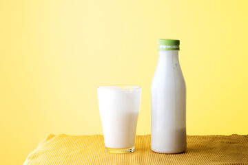 bottle and glass of dairy product on a yellow background