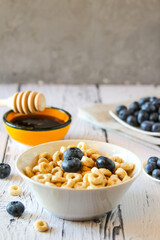 Honey rings with blueberries in a bowl on the table wooden background. Copy space. Flat lay. Horizontal orientation.