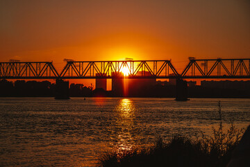 Naklejka na ściany i meble Railway bridge over the river during sunset