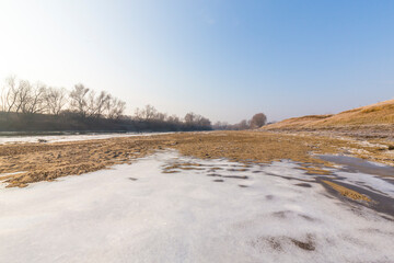 Cold winter morning on a wild river bank, with frost and fresh snow