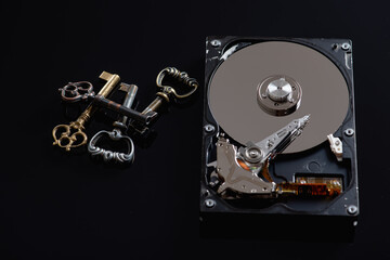 Hard drive or hard drive on a black reflex background, information protection next to it lie antique metal keys, low key, there is a place for the inscription 