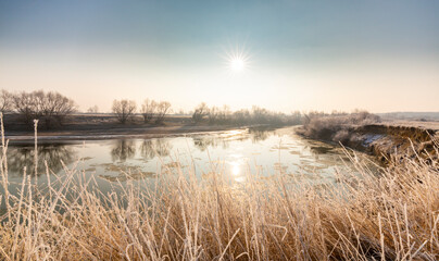 Cold winter morning on a wild river bank, with frost and fresh snow
