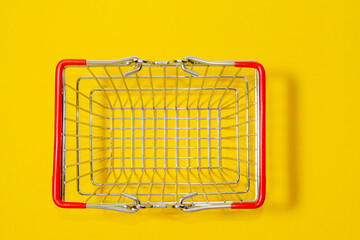 Top view of supermarket shopping basket on a yellow background. Black Friday sale concept.
