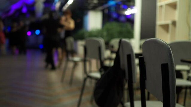 Argentine tango, milonga. Chair backs against the background of couples dancing tango at a party.