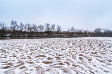 Abstract shapes with sand dunes covered by fresh powder snow, in a wild river bed, in winter