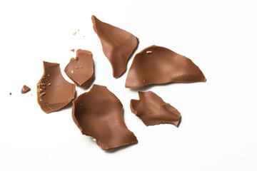 Broken pieces of milk chocolate on white table