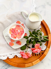 Cup of milk for a better nights sleep with rose petals on white background. Image with copy space, top view