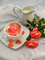Cup of milk for a better nights sleep with rose petals on white background. Image with copy space, top view