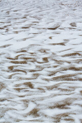 Abstract shapes with sand dunes covered by fresh powder snow, in a wild river bed, in winter