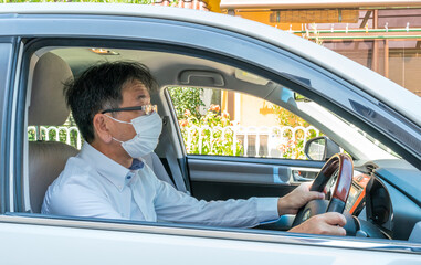 マスクをした中年男性が車を運転している