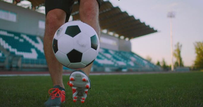 Tilt up with slow motion of male from professional soccer league juggling ball on leg in outdoor playing field on sunny summer day