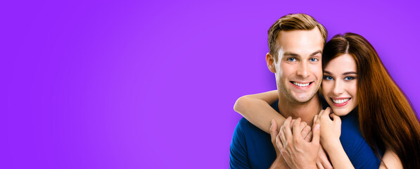 Smiling young amorous couple. Portrait image of embracing caucasian models at happy in love studio concept, isolated over violet purple color background. Man and woman posing together, with copy space