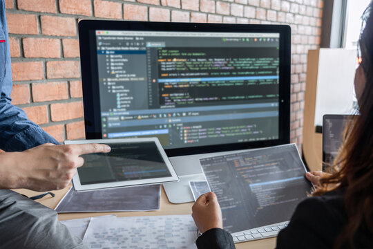 Two professional programmer cooperating and working on web site project in a software developing on desktop computer at company, codes and typing data code, Programming with HTML, PHP and javascript