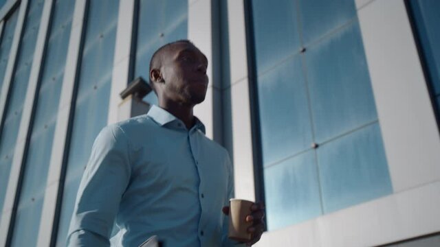 Successful African American business man walks down the street near a business office