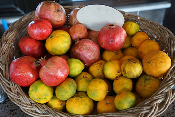 Wooden fruit basket of fresh pomegranate and orange