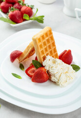 Belgian waffles with strawberries, cream and fresh mint.